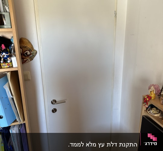 דלת לבנה עם ידית מתכת בחדר קטן